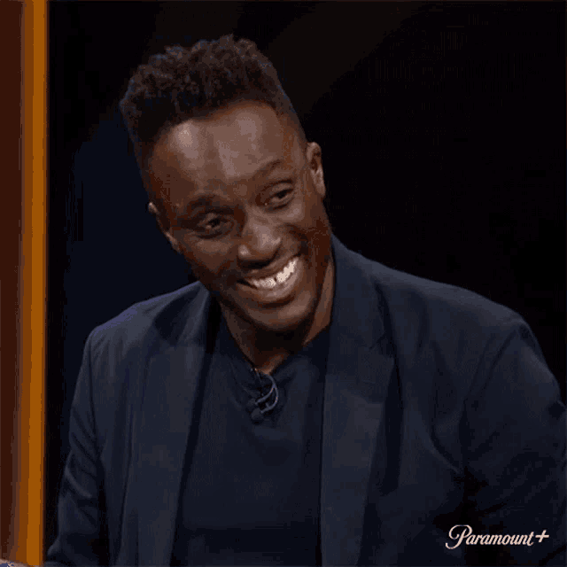 a man in a suit is smiling in front of a sign that says paramount