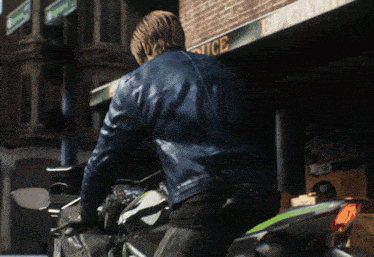 a man in a blue leather jacket is riding a motorcycle in front of a store that says police