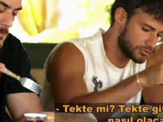 a man is sitting at a table with a fork in his hand while another man talks to him