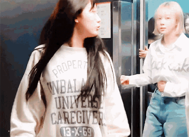 a woman wearing a white sweater that says proper ndala universe caregiver 13 x 69