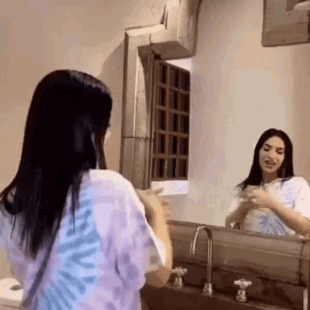 a woman is standing in front of a mirror in a bathroom .