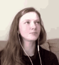 a woman wearing earbuds is sitting on a couch .