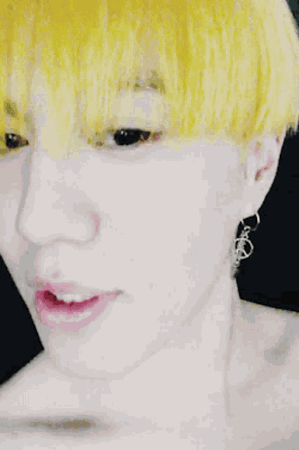 a close up of a person 's face with yellow hair and silver earrings
