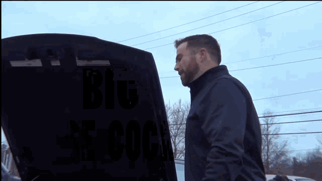 a man looking under the hood of a black car