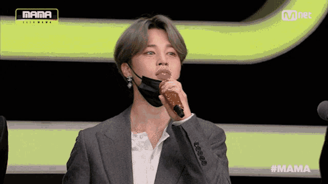 a man wearing a face mask is holding a microphone in front of a mnet logo