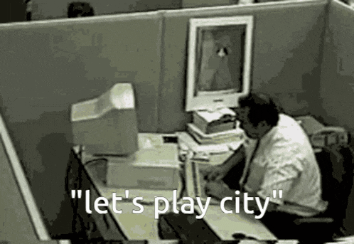 a man is sitting at a desk in front of a computer with the words " let 's play city " written on the screen .