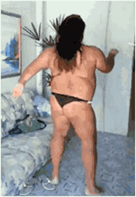 a man in a bikini is dancing in a living room