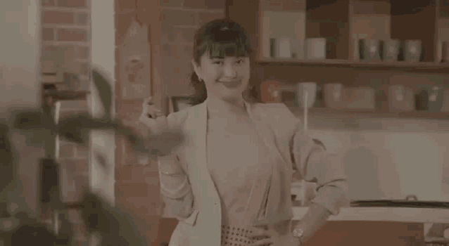 a woman is standing in front of a brick wall in a kitchen .