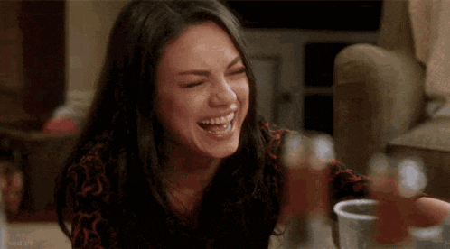a woman is laughing and crying while sitting at a table .