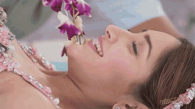 a woman laying down with a flower in her mouth and the word nb on the bottom