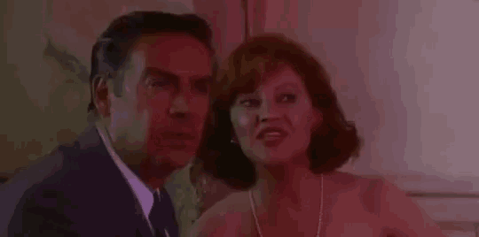 a man and a woman are sitting next to each other and looking at each other .
