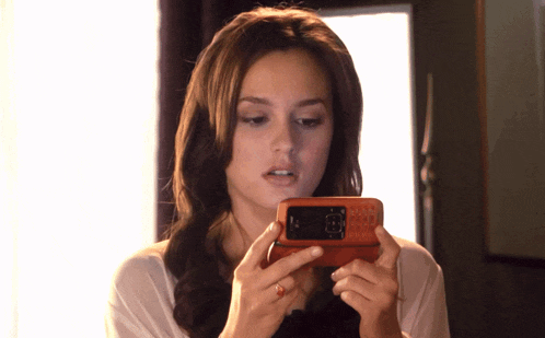 a woman is holding a cell phone in her hands and looking at the screen