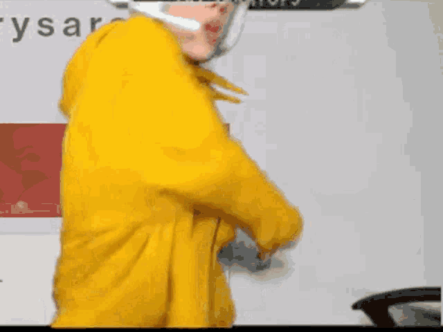 a person wearing a yellow hoodie is dancing in front of a sign that says ' ysaratops '