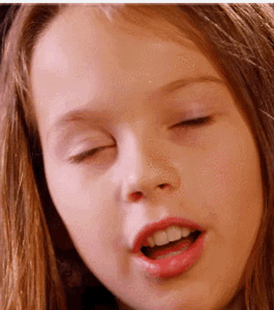 a close up of a girl 's face with her eyes closed and her mouth open