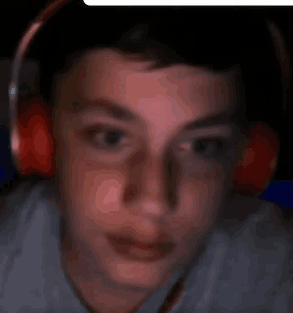 a young boy wearing red headphones looks at the camera