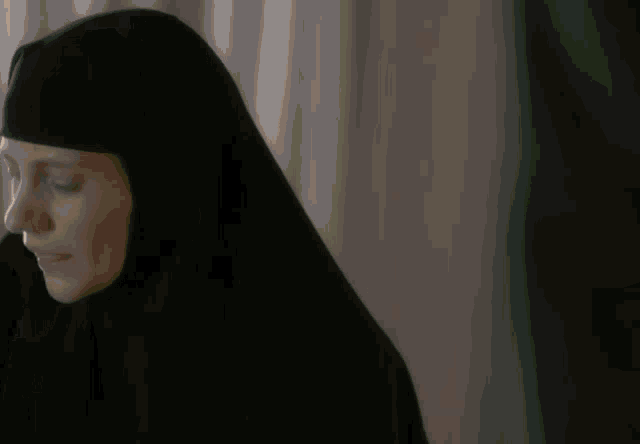 a man is covering his face with his hand in a dark room