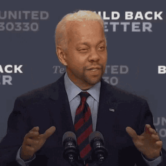 a man in a suit and tie stands in front of a microphone with the word fraud written in front of him