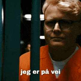 a man wearing glasses behind bars with the words jeg er på vei written below him