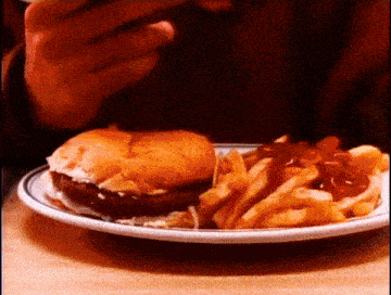 a person is eating a hamburger and french fries on a white plate