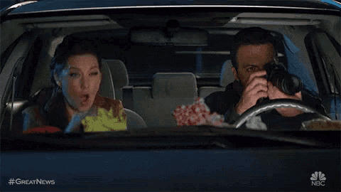 a man is taking a picture of a woman in a car with #greatnews written on the bottom
