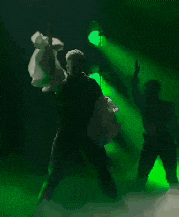 a man is dancing on a stage in front of green lights .