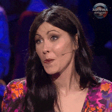 a woman is sitting in front of a microphone with the word adivina on the bottom