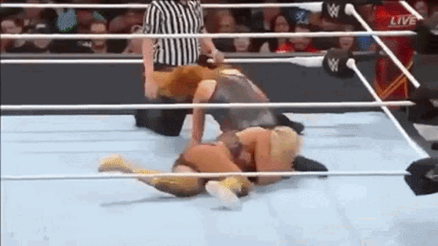 two women are wrestling in a wrestling ring with a referee .