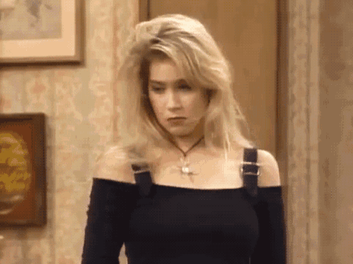 a woman wearing a black off the shoulder top is standing in a room .