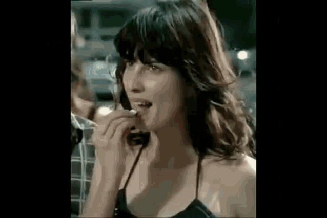 a woman in a black top is eating a piece of meat .