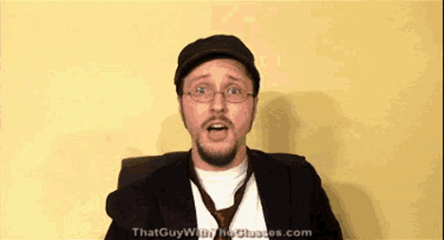 a man wearing glasses and a hat with the website thatguywiththeglasses.com in the corner