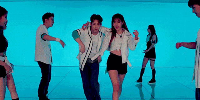 a group of people are dancing on a stage in a room with purple lights .