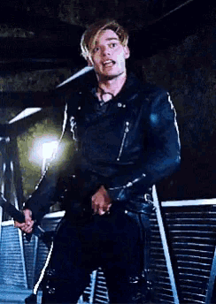a man in a black leather jacket is holding a sword