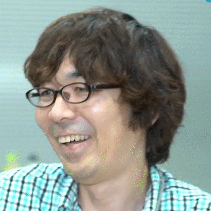 a man wearing glasses and a plaid shirt is smiling and looking at the camera .