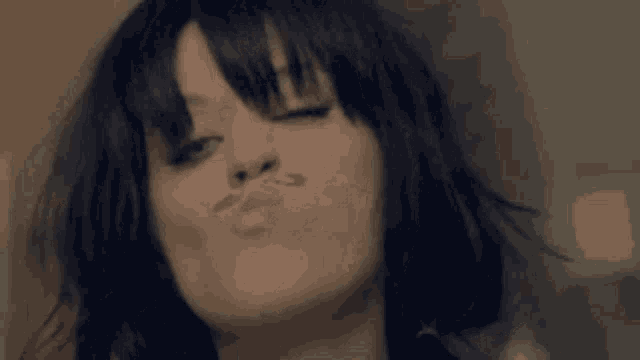 a close up of a woman making a funny face with her eyes closed and her hair blowing in the wind .