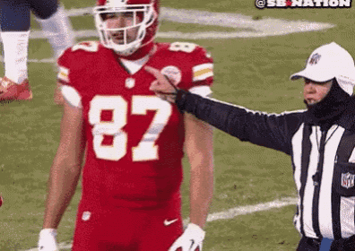 a football player wearing a red jersey with the number 87 on it is standing next to a referee .