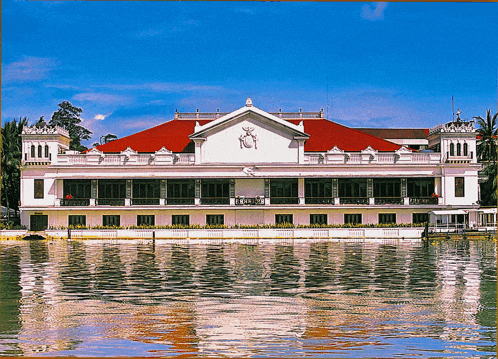 a large building with a red roof is reflected in a body of water