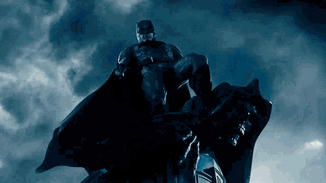 a man in a batman costume is standing on a statue