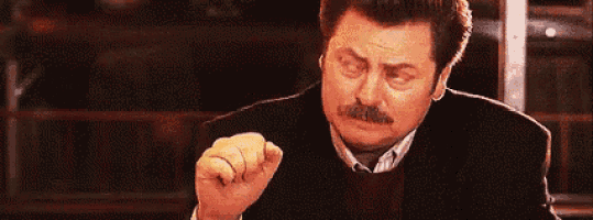 a man with a mustache is sitting at a table eating a piece of food .