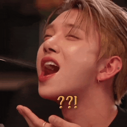 a close up of a young man making a funny face with his mouth open and a question mark on his neck .