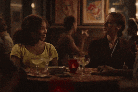 two women sit at a table with martini glasses and a red cup