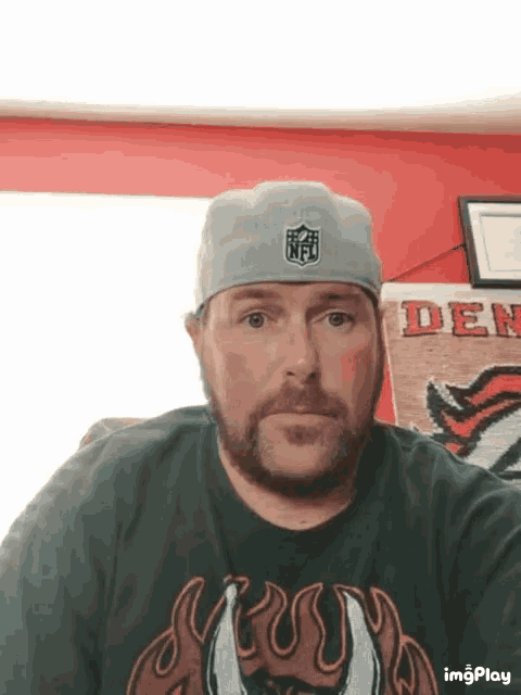 a man wearing a nfl hat and a t-shirt with flames on it