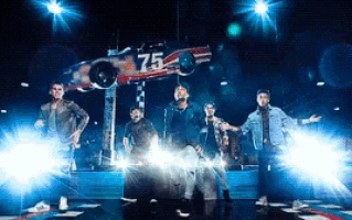 a group of men are standing in front of a race car that has the number 75 on it
