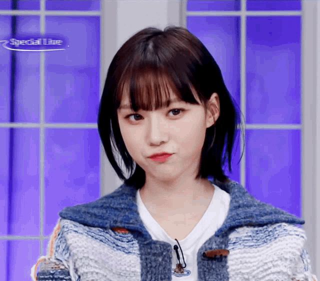 a woman in a blue and white sweater is standing in front of a window that says special live