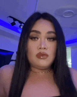 a woman with long black hair and red lips is making a funny face in a room .