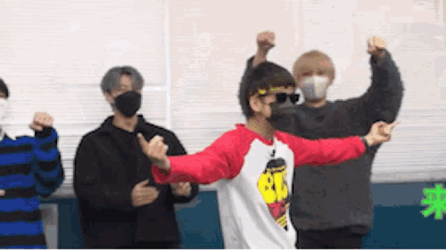 a group of young men wearing face masks and sunglasses are dancing together .
