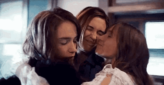 three women are hugging and kissing each other on the cheeks .