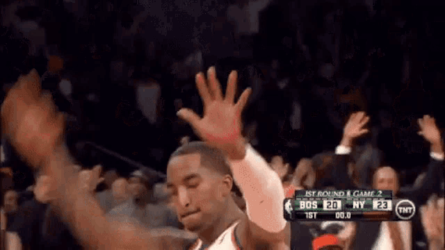 a basketball player is raising his hands in the air during a game