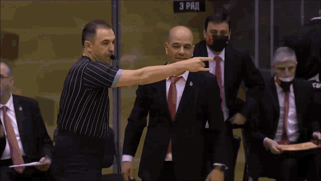 a man in a suit and tie talks to a referee in front of a sign that says " 3 rad "