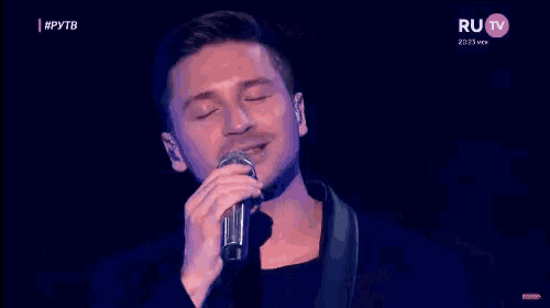 a man is singing into a microphone on a tv screen .