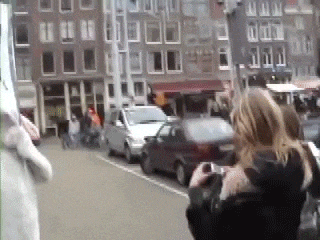 a woman is taking a picture of a street with cars parked on the side of it